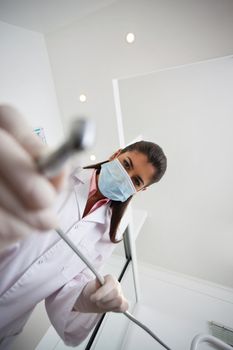 Low angle view of female dentist holding drill