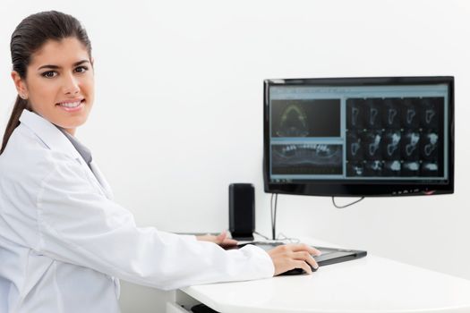 Dentist with teeth x-ray on screen.