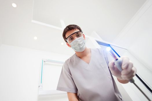 Dentist wearing mask holding UV light