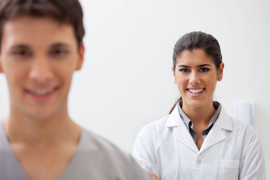 Portrait of confident female doctor smiling with colleague standing in front of her