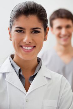 Portrait of happy female doctor with practitioner standing in background