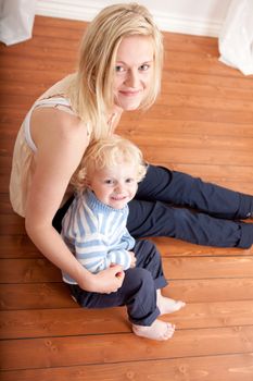 Mother with her toddler son looking at the camera from the floor