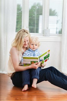 Mother and baby reading book while sitting on floor