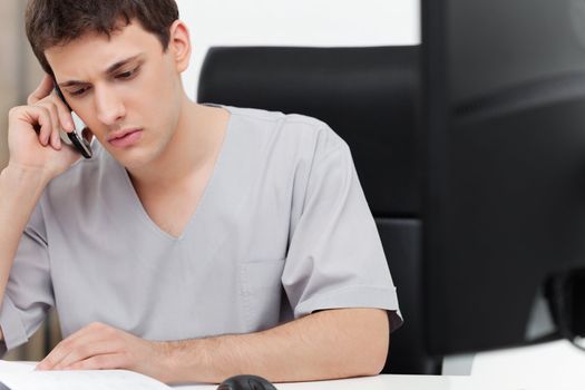 Serious young dentist having conversation on mobile phone