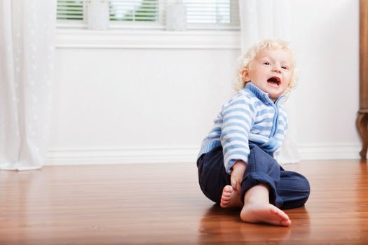 Sweet little boy with mouth open sitting on floor