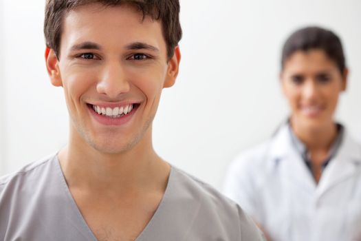 Portrait of happy male doctor standing with female doctor standing in background