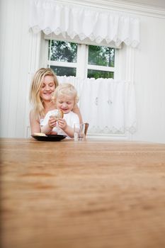 Smiling young mother with baby boy looking at bread at dining table