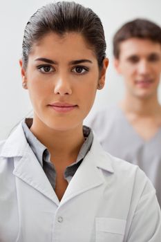 Portrait of confident female doctor with practitioner standing in background