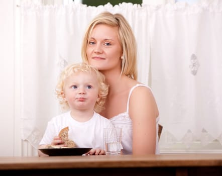 A happy content mother and child sitting at a table eating lunch