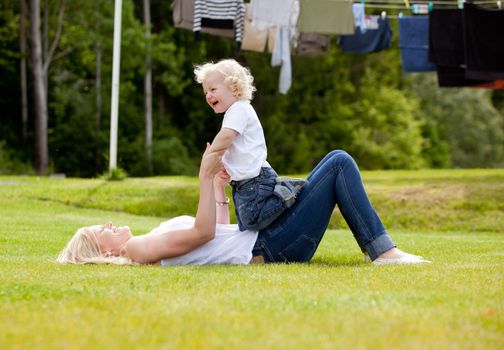 A mother and son having fun, playing outdoors in the grass