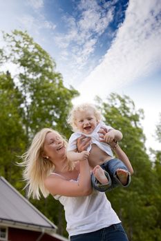 A mother and happy excited son playing together outdoors