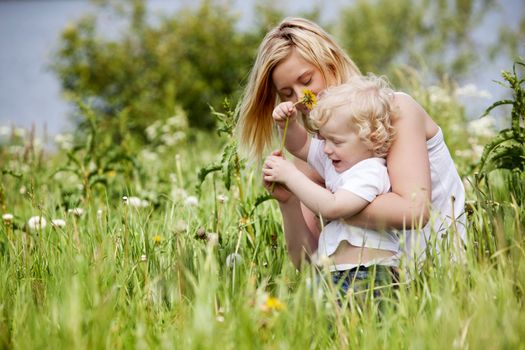 A mother and son having fun playing with flowers in a grass field