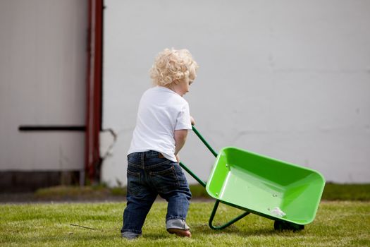 A young child pushing a wheelbarrow