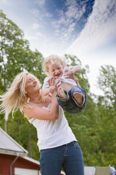 Young female playing with her little child in garden