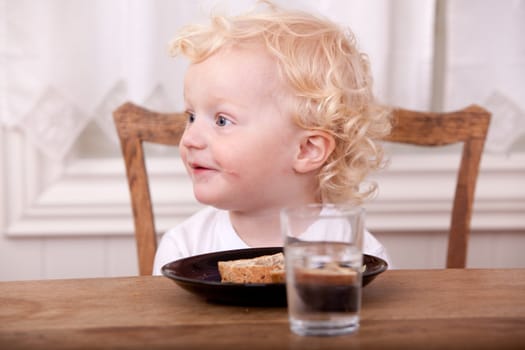 A young boy at the lunch table, looking off camera and smiling