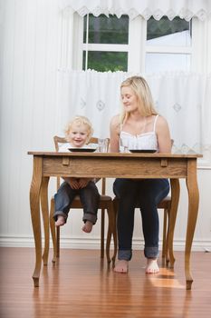 Young woman looking at her cute child at dining table