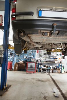 Car under repair on service lift in garage