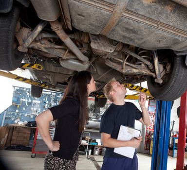A young mechanic showing a female customer what was done to her car