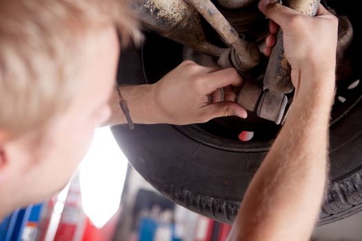 A mechanic inspecting a shock absorber on a car