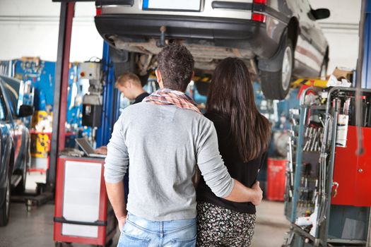 Rear view of young couple with mechanic in the background
