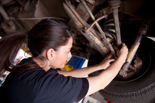 A woman mechanic working on a car, checking a cv boot