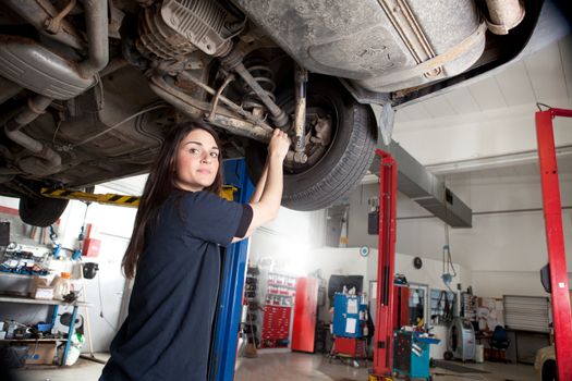 Portrait of a woman mechanic working on the underside of a car