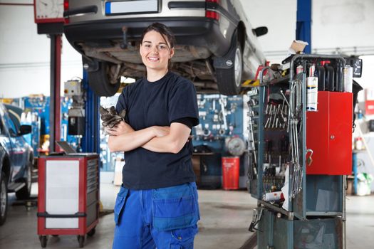 Portrait of smiling young female mechanic with arms crossed in auto repair shop