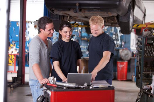 Team of mechanics looking at a laptop in a auto repair shop