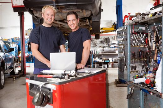Portrait of mechanics with laptop in auto repair shop