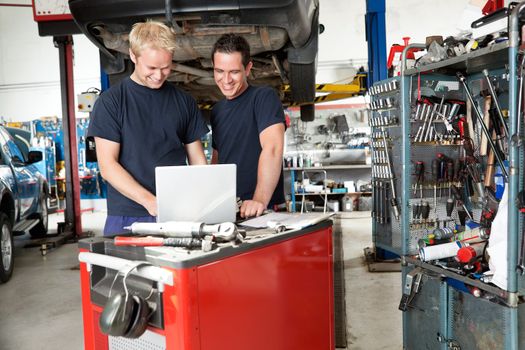 Mechanics working on laptop in auto repair shop