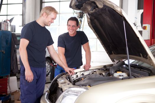 Two mechanics looking at and working on a car in a repair shop