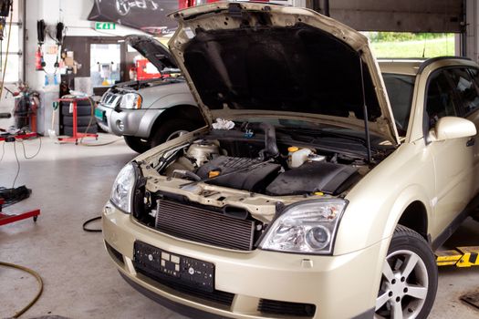 A car in a professional auto repair shop with hood up