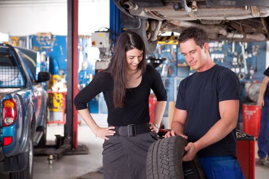 A mechanic showing the tread of a tire to a female customer