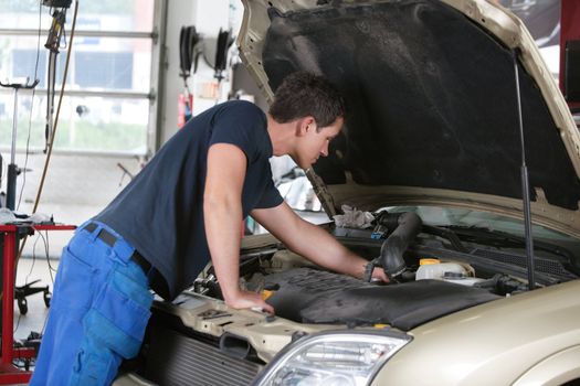 Auto mechanic working on a car in garage