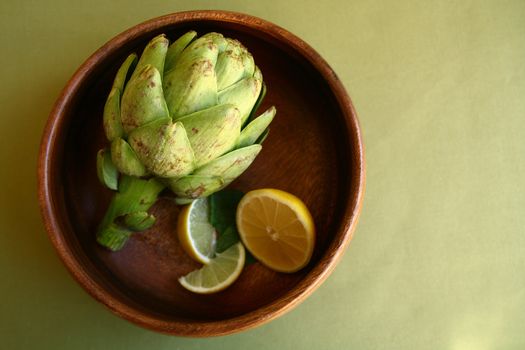 Fresh Artichoke in Wooden Bowl With Lemons