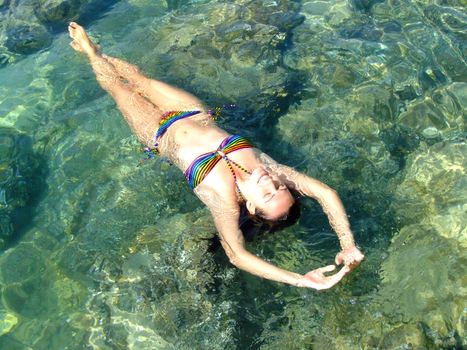 Young woman in bikini floating in clear shallow water