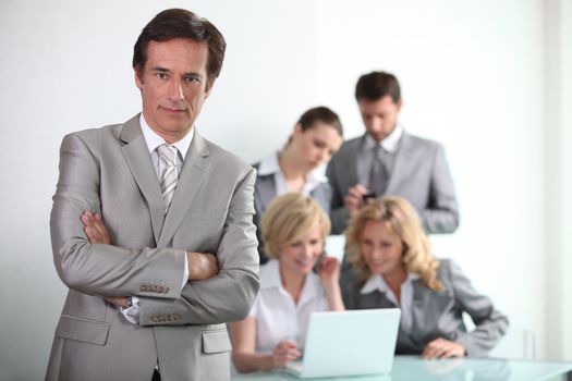 Confident male executive with his team of colleagues in the background