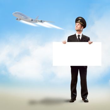 pilot in the form of holding an empty billboard on the background of sky and flying plane, place for text