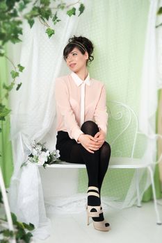 A woman in a pink blouse sitting on a bench in the green.