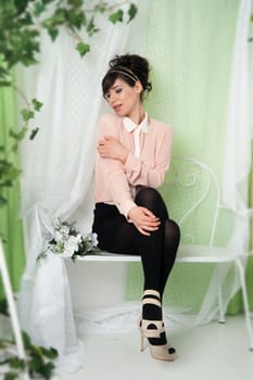 A woman in a pink blouse sitting on a bench in the green.