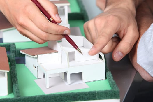 Hands pointing to a model house