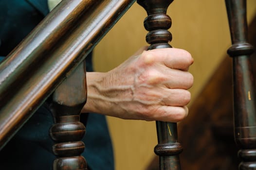 old woman wrinkled hands holding of handrail