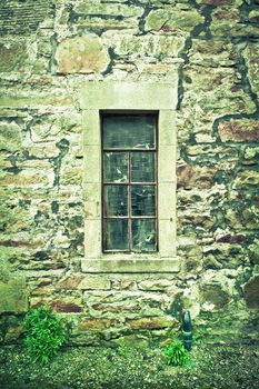 A cracked window in a derelict stone cottage