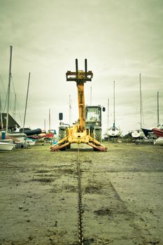 A yellow boat winch with a chain at a boat yard