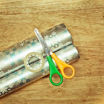 Scissors, tape and wrapping paper on a wooden table