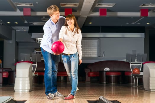 guy hugs her friendgirl, playing together in bowling