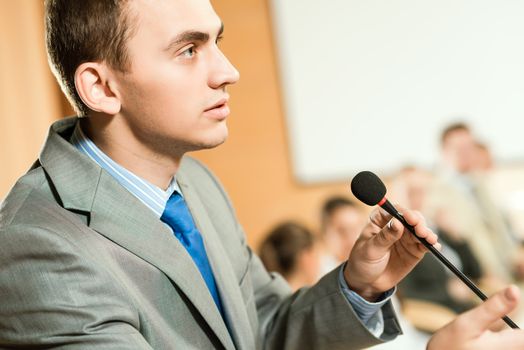 male speaker looks into the room and said into the microphone, speech at the conference