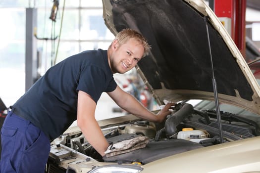 Portrait of a smiling mechanic working on a car in garage