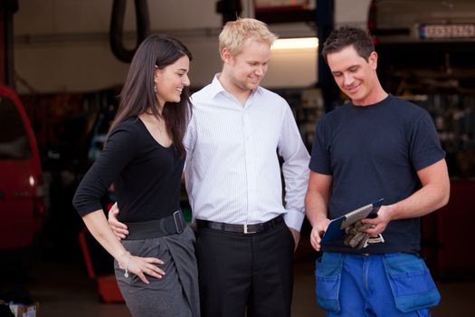 A happy customer couple receiving repair report from smiling man mechanic