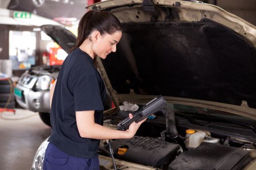 Woman mechanic looking at electronic diagnostics tool